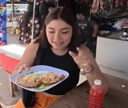 La Gaby holding a plate of tostadas at an unnamed Belmopan market stall